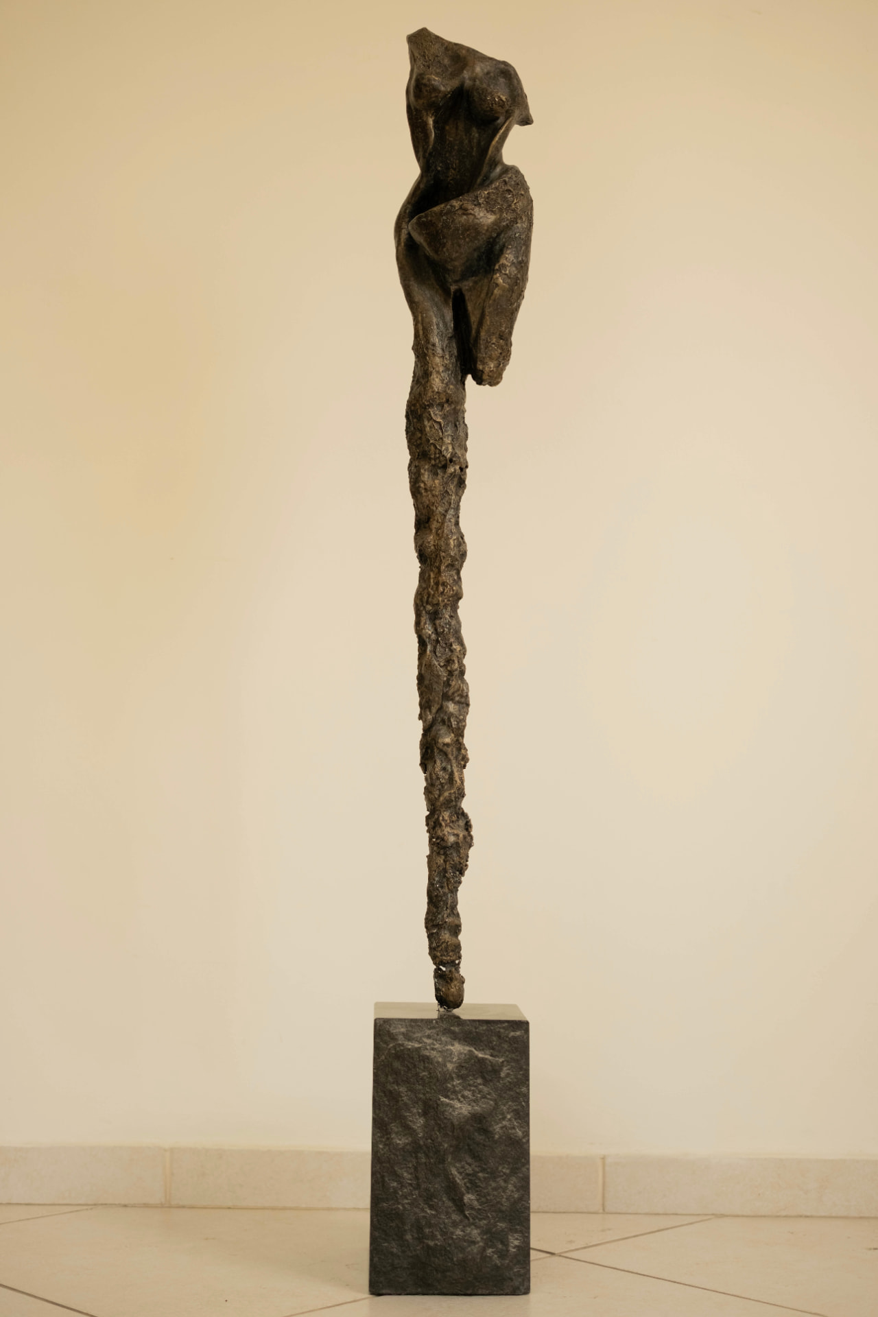 Sentinel — elongated bronze figure on a dark stone base