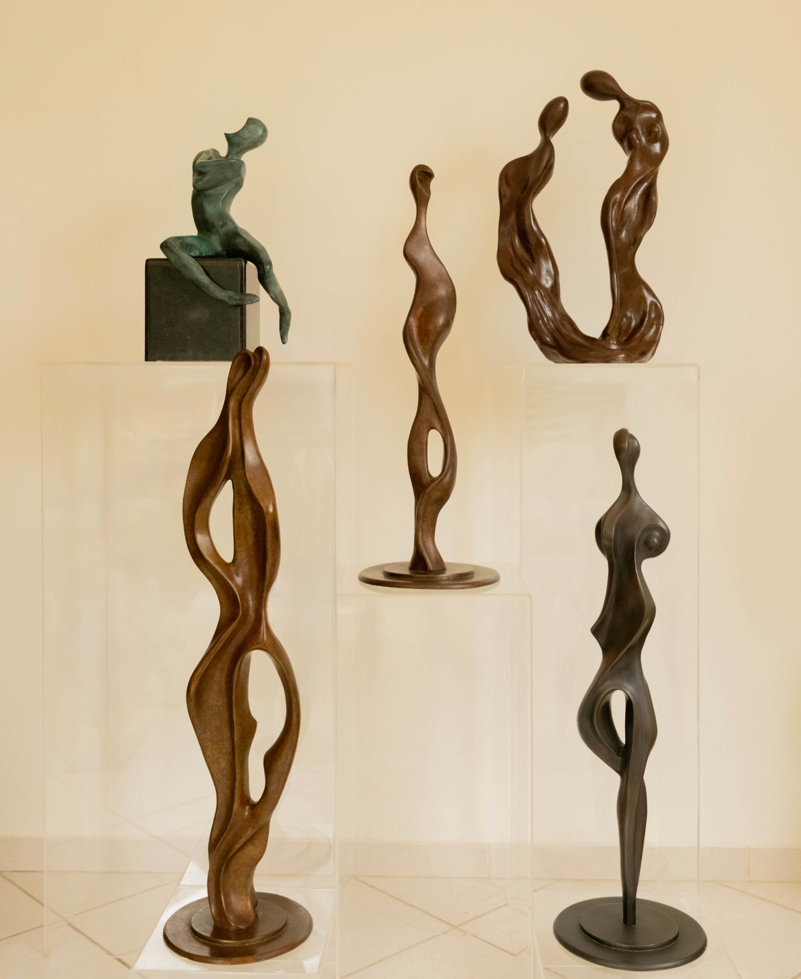 Group of elongated bronze figures on acrylic plinths